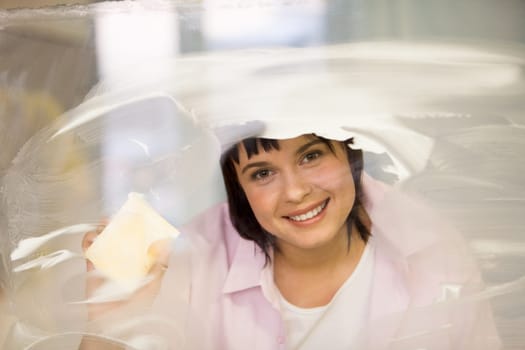 Portrait of young female washing window and smiling