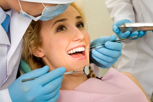 Image of young lady with dentist over her before checking oral cavity