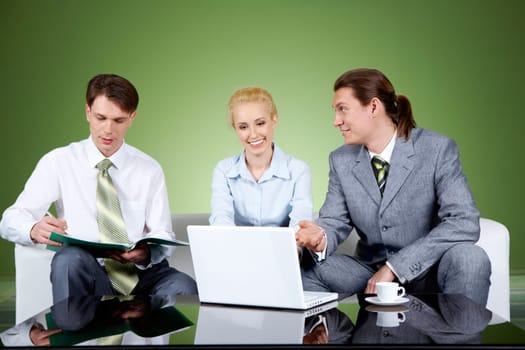 Portrait of businesspartners communicating at meeting with their colleague sitting near by