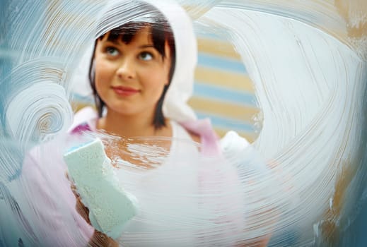 Portrait of young female washing window and smiling