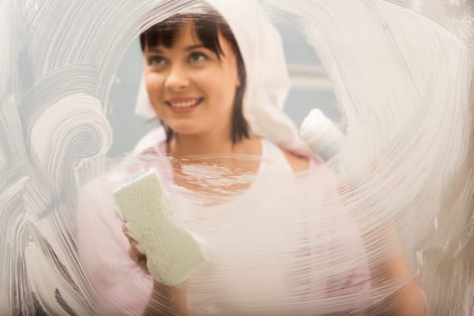 Portrait of young female washing window and smiling
