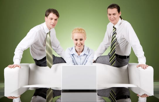 Photo of attractive woman typing on laptop with two men sitting behind her