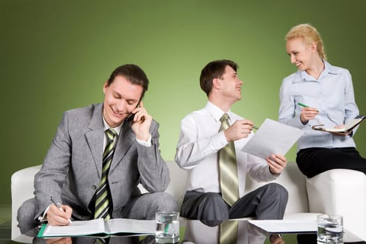 Image of smiling businessman calling by phone while his partners discussing new plans in office