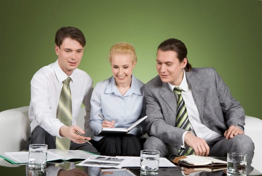 Image of successful business people sitting around table and interacting
