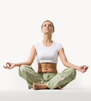 Image of young pretty woman sitting in pose of lotus and looking upwards