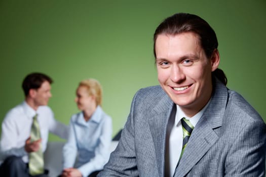 Portrait of people interacting with smiling businessman in front looking at camera