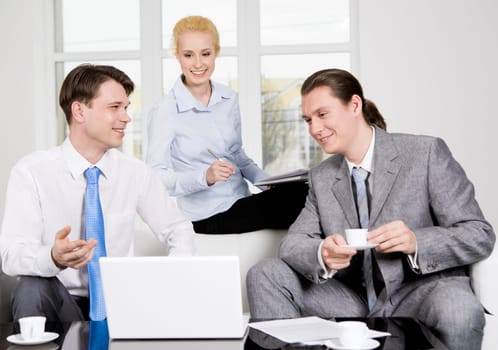 Portrait of successful co-workers sharing their ideas in office while looking at laptop monitor