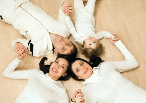 Above view of family members lying on the floor and holding each other by hands