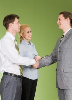 Portrait of two businessmen shaking hands after signing contract with pretty secretary standing near by