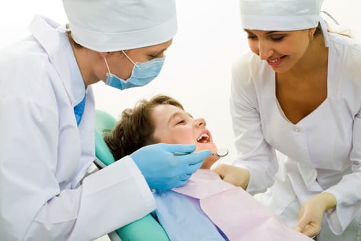 Image of dental examining being given to little boy by dentist and his assistant