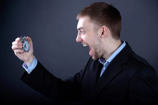Portrait of young man looking at clock and shouting