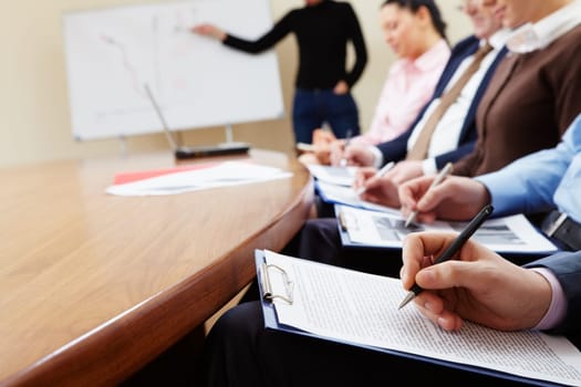 Close-up of businesspeople hands with documents writing at lecture