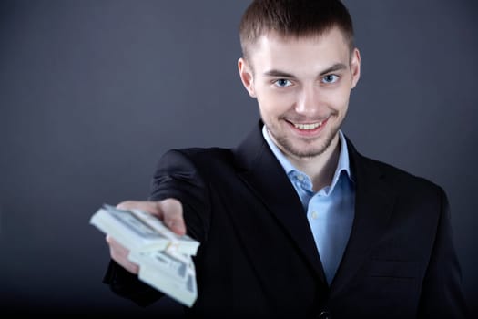Portrait of successful businessman giving money to you