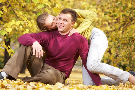 Young woman kissing her husband outdoors in autumn park