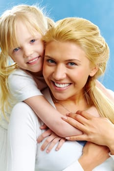 Portrait of young happy woman holding daughter on her back