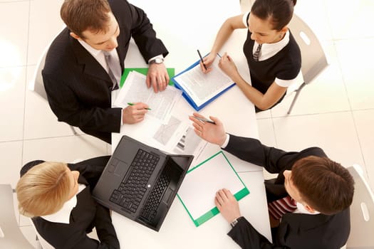 Above view of friendly workteam discussing business plan at meeting