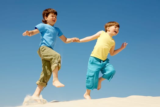 Photo of happy boys running down sandy beach and laughing