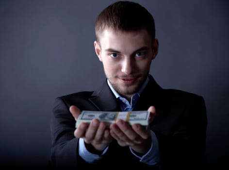 Portrait of serious businessman giving money to you