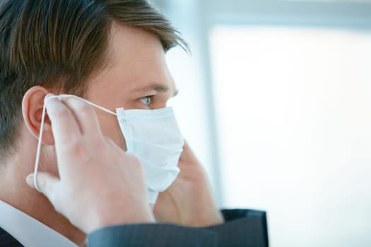 Portrait of businessman putting protective mask on his face