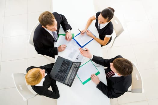 Above view of friendly workteam discussing business plans at meeting
