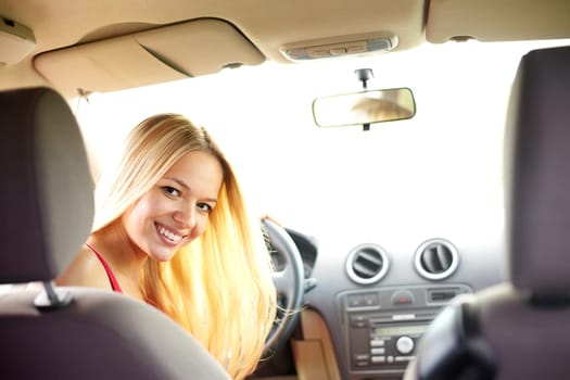 Happy blond woman looking at camera in the car