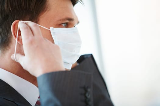 Portrait of businessman putting protective mask on his face
