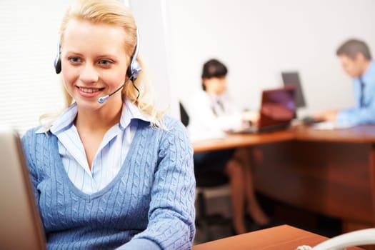 Pretty secretary speaking on headphone in the office