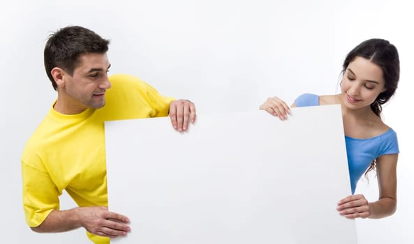 Positive man and woman holding paper poster and looking at it
