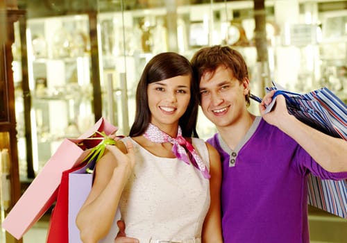 Portrait of joyful husband and wife after shopping looking at camera