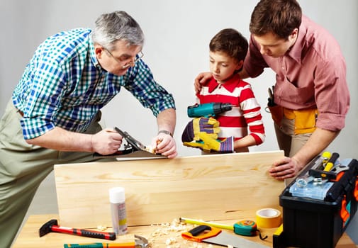 A grandfather and a father teaching a boy to work with plane