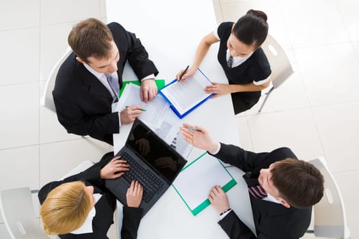 Above view of friendly workteam discussing business plan at meeting