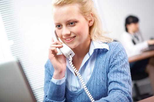 A young woman receptionist with a telephone receiver