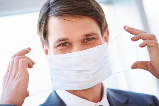Portrait of businessman holding protective mask before himself
