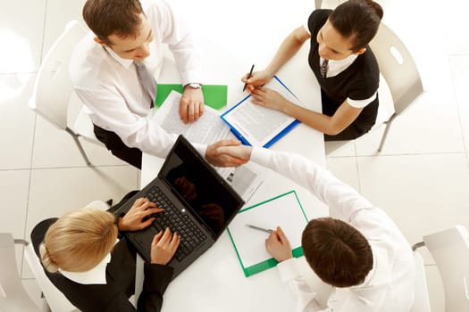 View from above of happy partners shaking hands at meeting