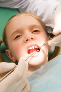 Close-up of little girl opening her mouth for dental checkup in stomatological office