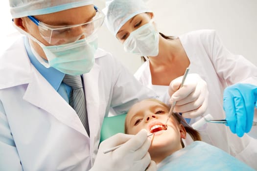 A dentist and a nurse curing little girls teeth