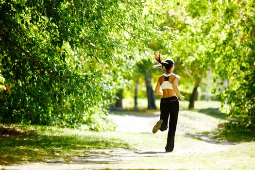 A young girl jogging in the park along trees