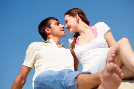 Photo of peaceful couple looking at each other with blue sky on background