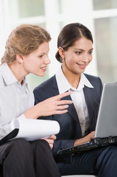 Portrait of two business women looking at the monitor of laptop