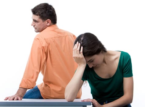 Depressed woman touching her head with husband sitting on table behind