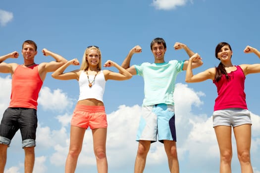 Four happy friends showing their muscles