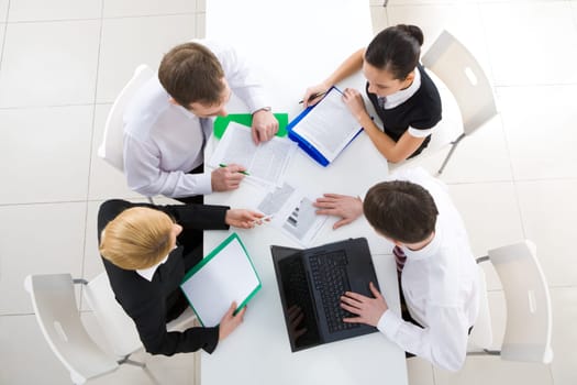 Above view of friendly workteam discussing business plan at meeting