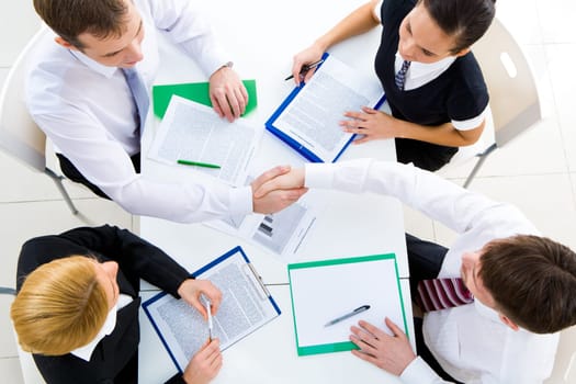 View from above of happy partners shaking hands at meeting