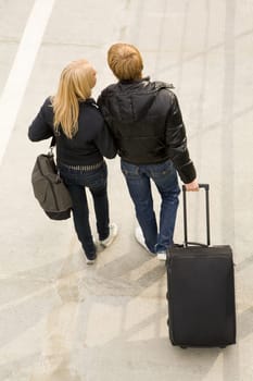 Above view of couple walking down trottoire with their baggage and chatting