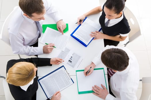 Above view of friendly workteam discussing business plan at meeting