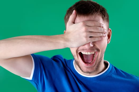 Portrait of young man closing eyes with hand and shouting