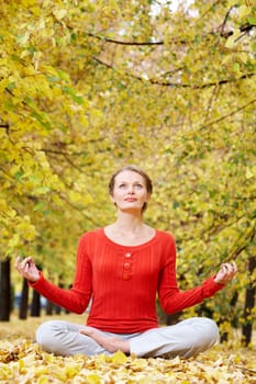 Portrait of young woman meditating outdoors in autumn