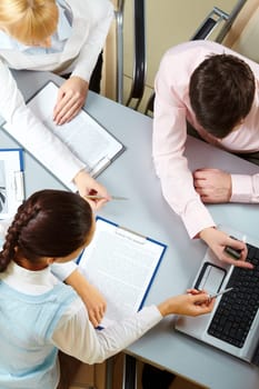 Above view of three business partners interacting at meeting