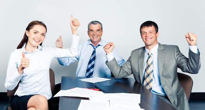 Team of three office workers showing a successful sign