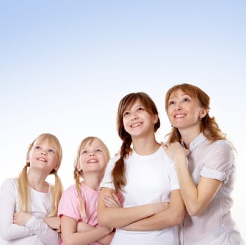 A young family of four looking upwards on blue background